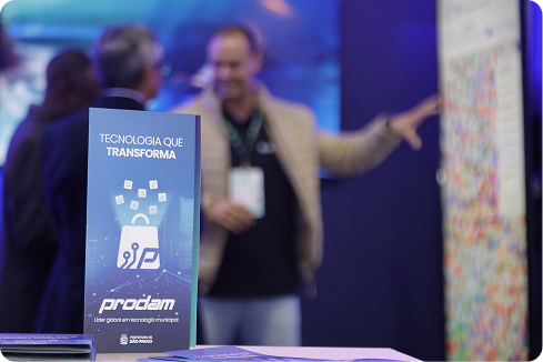 Evento Prodam Store: apresentação com banner 'Tecnologia que Transforma' e participantes ao fundo