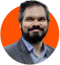 Homem branco de barba, utilizando um terno cinza